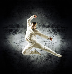 Naklejka na ściany i meble Sporty modern dancer over the dramatic background in sepia style