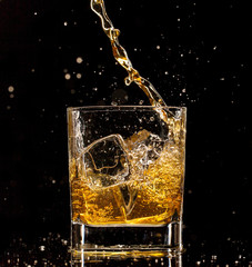 Whiskey glass with splash, isolated on black background