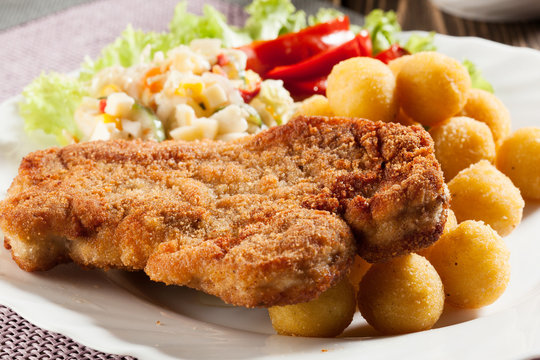 Breaded chop, prepared potatoes and salad. Mysterious light.