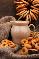 jar of milk, tasty bagels and spikelets on wooden background