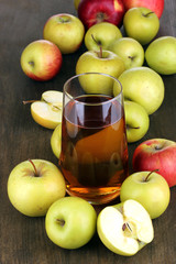 Useful apple juice with apples around on wooden table