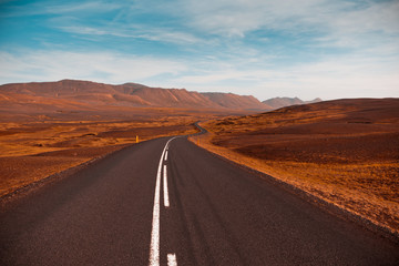 Highway through dry gravel lava field landscape under a blue sum