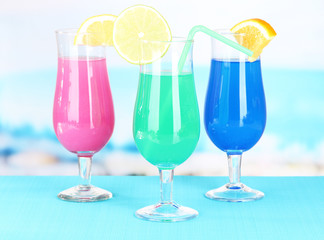 Glasses of cocktails on table near pool
