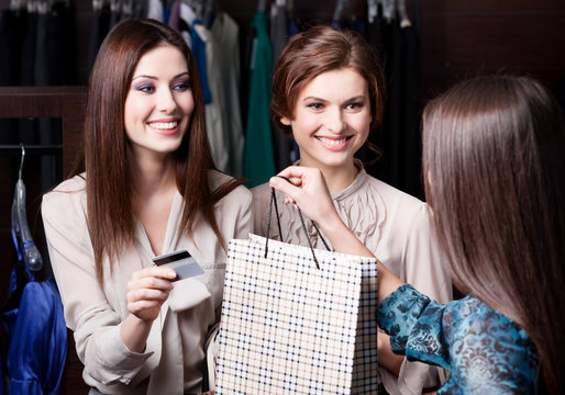 Pretty women pay charges account with credit card at the shop