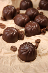 Chocolate candies and coffee beans, on beige paper background