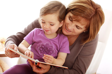 Eine Oma liest ihrer Enkeltochter aus einem Buch vor