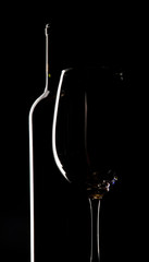 Botella y copa de vino, reflejo blanco sobre negro.