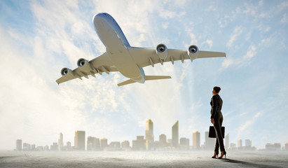 Business woman looking at airplane in sky