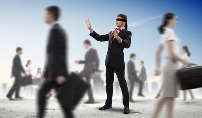 Businessman in blindfold among group of people