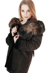 Elegant woman wearing brown sheepskin coat with fur on white.