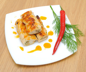 stuffed chicken rolls, chili and dill twig on a white plate