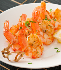 Fresh grilled shrimps with lemon on white plate