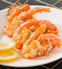 Fresh grilled shrimps with lemon on white plate