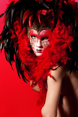 Naked woman in venetian mask over red