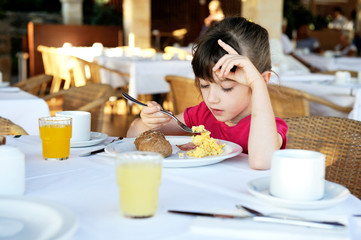 Little girl eating breakfast in outdoor cafe