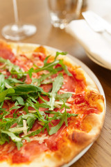 Pizza with arugula on table