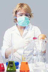 woman in protective mask tests apple specimen in chemical lab