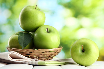 Ripe green apples with leaves in basket,