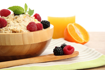 tasty oatmeal with berries and glass of juice, on wooden table