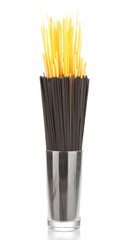 Black and yellow spaghetti in glass isolated on white