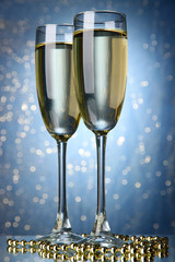 Two glasses of champagne on bright background with lights