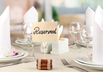 Reserved sign on restaurant table with empty dishes and glasses