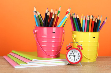 Colorful pencils in two pails with copybooks