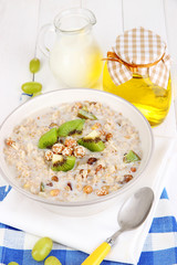 Useful oatmeal in bowl with fruit on wooden table close-up