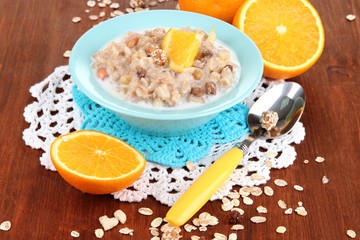 Useful oatmeal in bowl with fruit on wooden table close-up