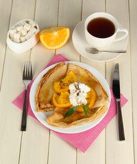 Pancakes with orange on wooden table
