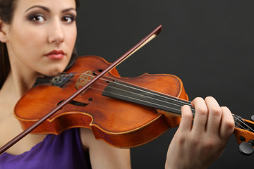 Beautiful young girl with violin on grey background