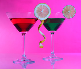 Alcoholic cocktails in martini glasses on pink background