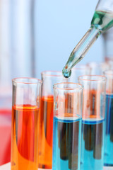 Laboratory pipette with drop of color liquid over glass test