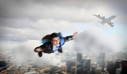 Young businessman flying with parachute on back