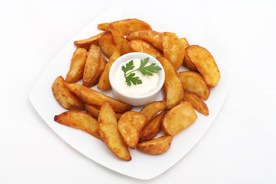 Fried potato wedges with white sauce on white plate