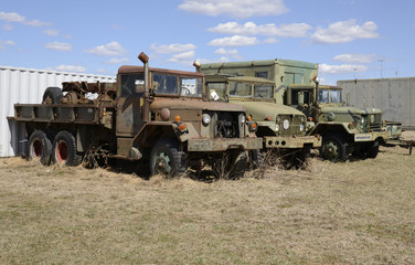 three old army vehicles parked in a grass field