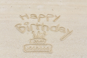 Happy Birthday with cake written in sand