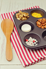 Cupcake ingredients in oven tray over red striped tablecloth