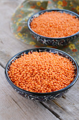 Oriental bowls with red lentils on wooden background