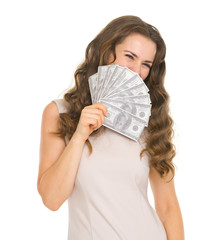 Portrait of happy young woman hiding behind fan of dollars