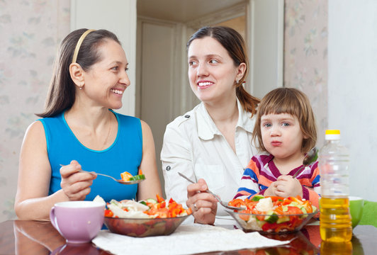  women with baby girl eats vegetables salad