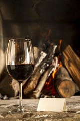 Copa de vino tino con fuego de chimenea de fondo.