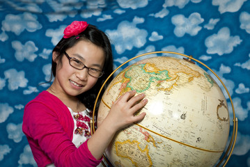 Fototapeta premium Young girl points to China on a globe