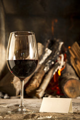 Copa de vino tino con fuego de chimenea de fondo.