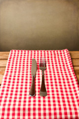Fork and knife on red tablecloth over grunge background