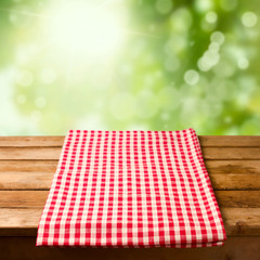 Empty wooden table with tablecloth over bokeh background