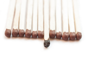 A row of matches with one burnt.
