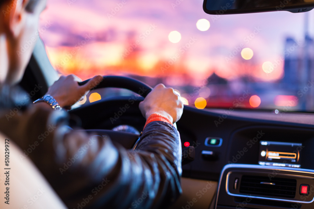 Wall mural man driving his modern car at night in a city