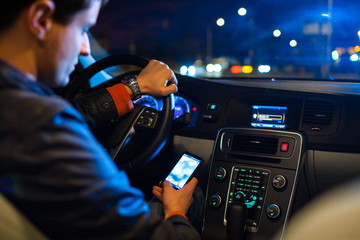 Man driving his modern car at night in a city