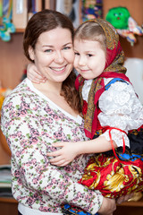 Fototapeta premium Happy mother holding small girl in Russian traditional clothes